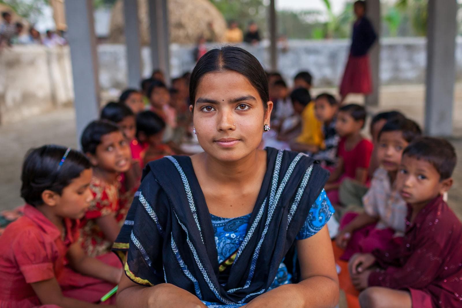 A teacher sitting with her students in an outdoor classroom